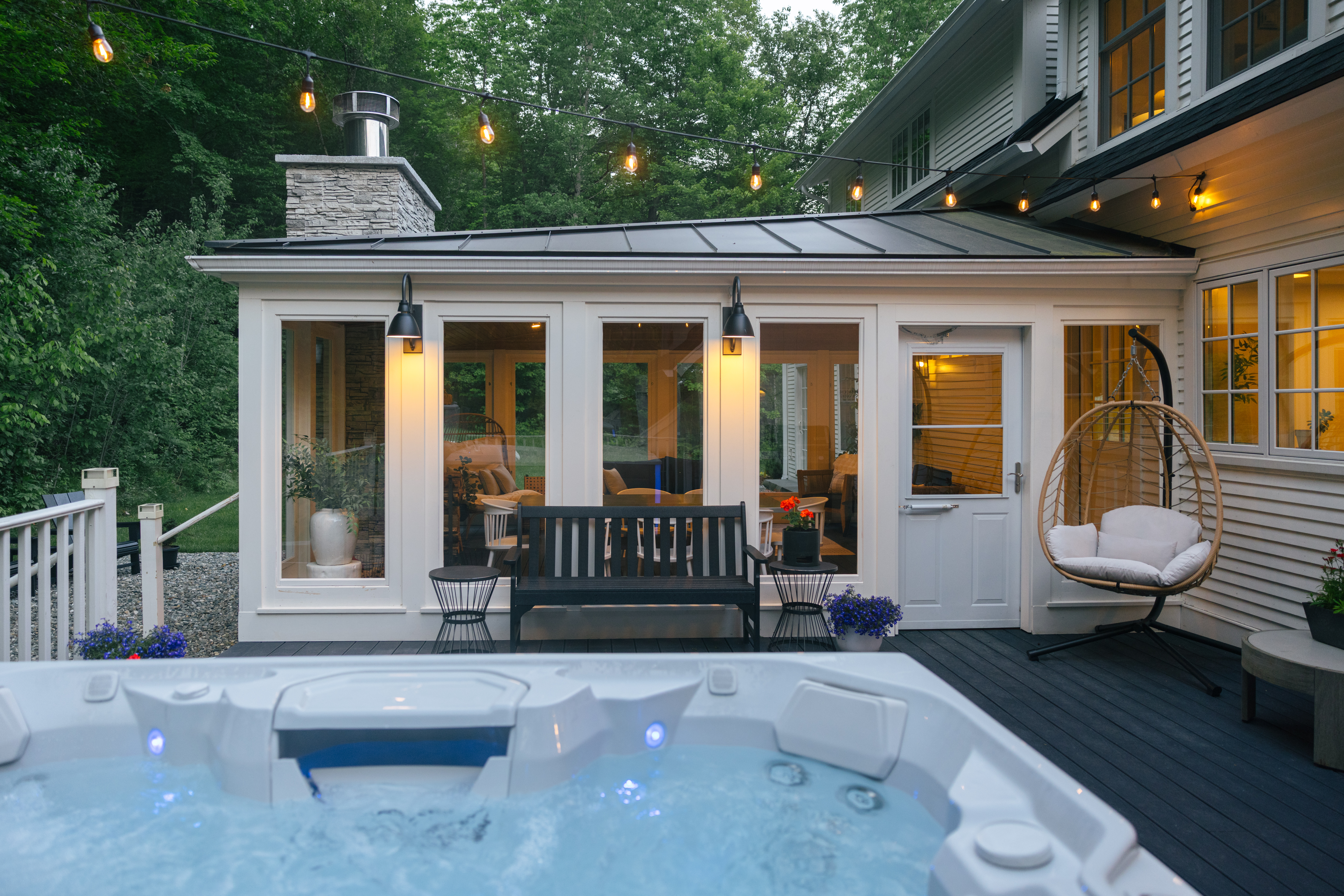 Outdoor hot tub next to a covered porch with seating at Mile Away